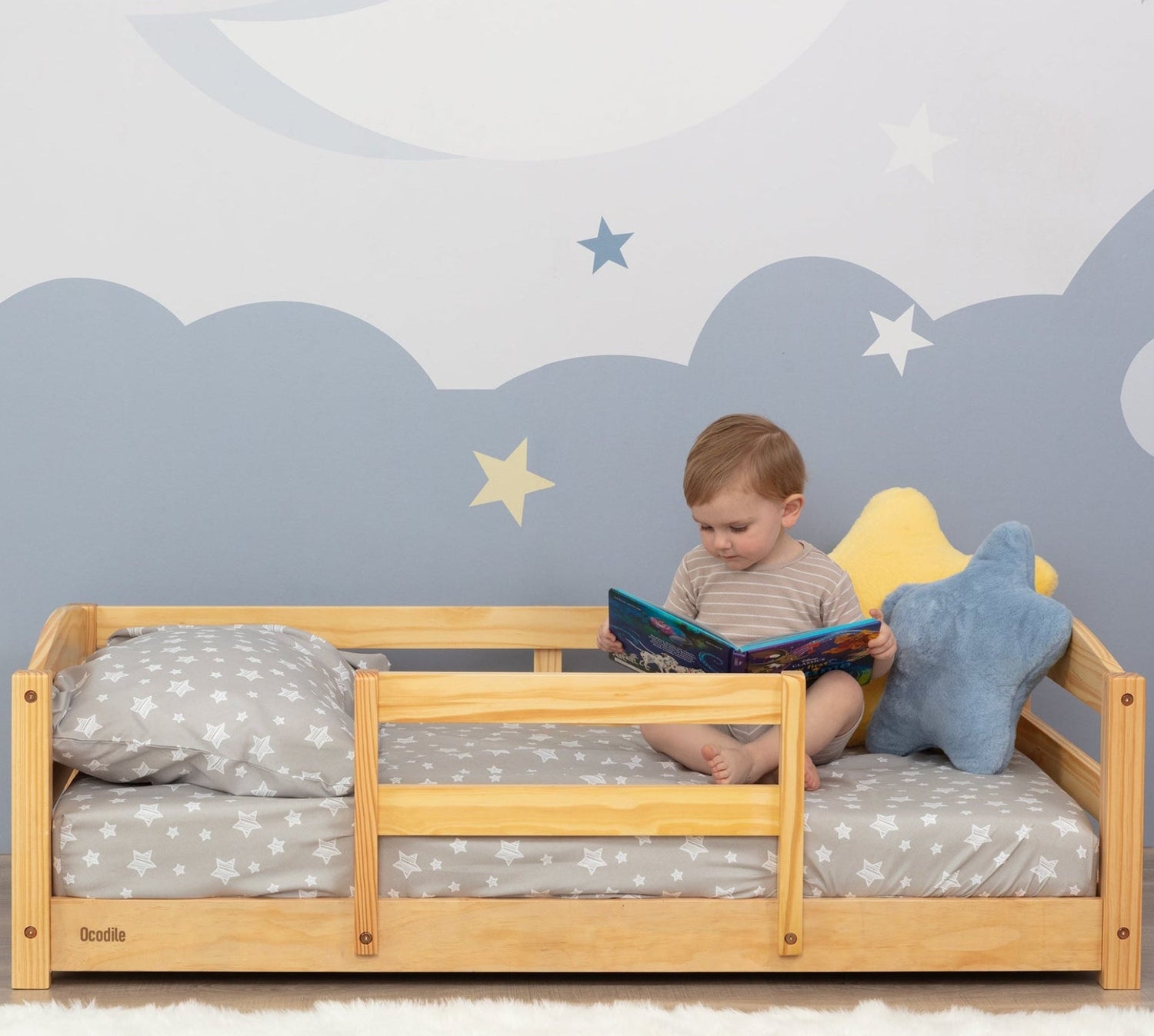 Child reading a book on a wooden floor bed Montessori type