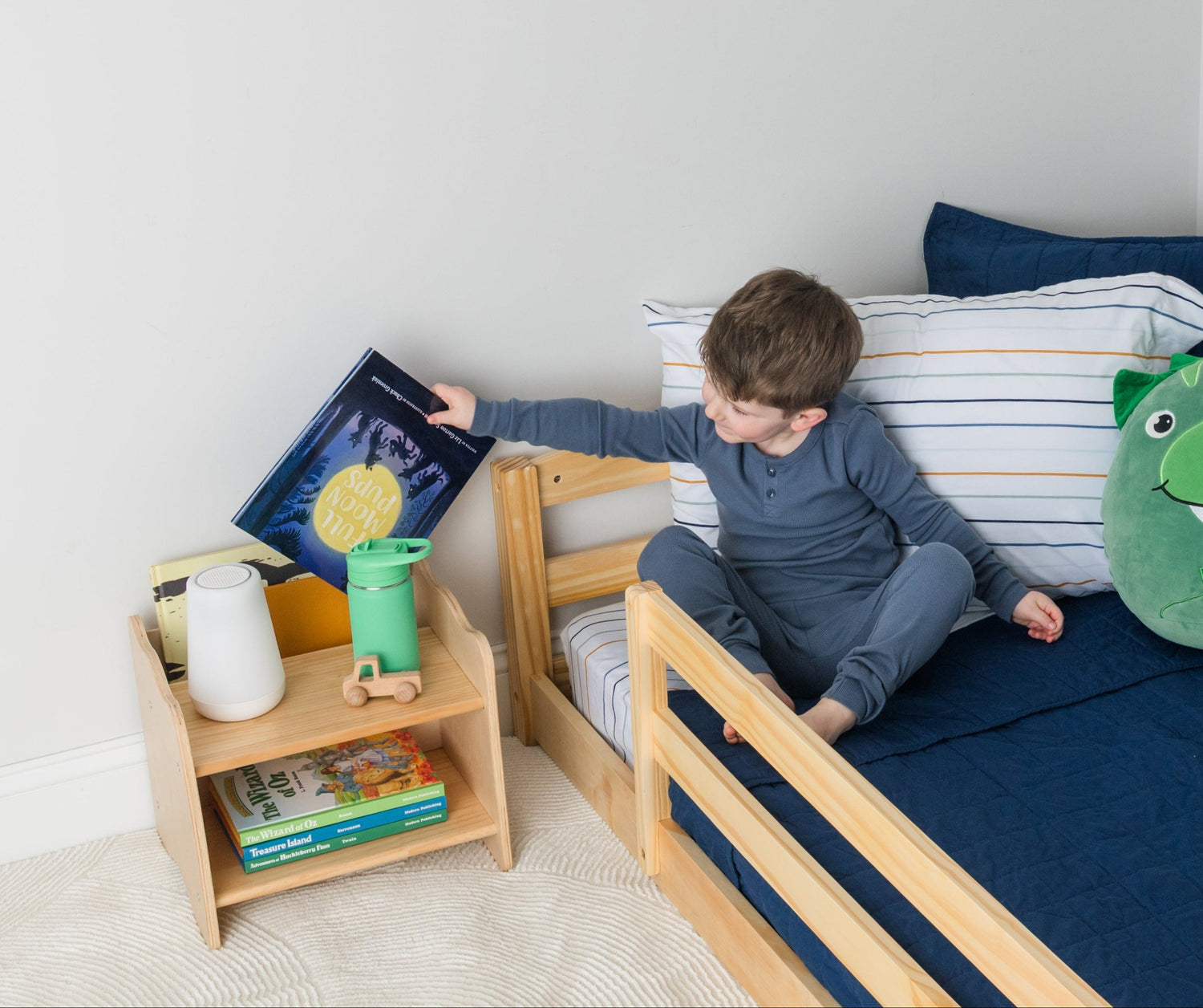 Toddler grabbing a book from his nightstand with books pocket