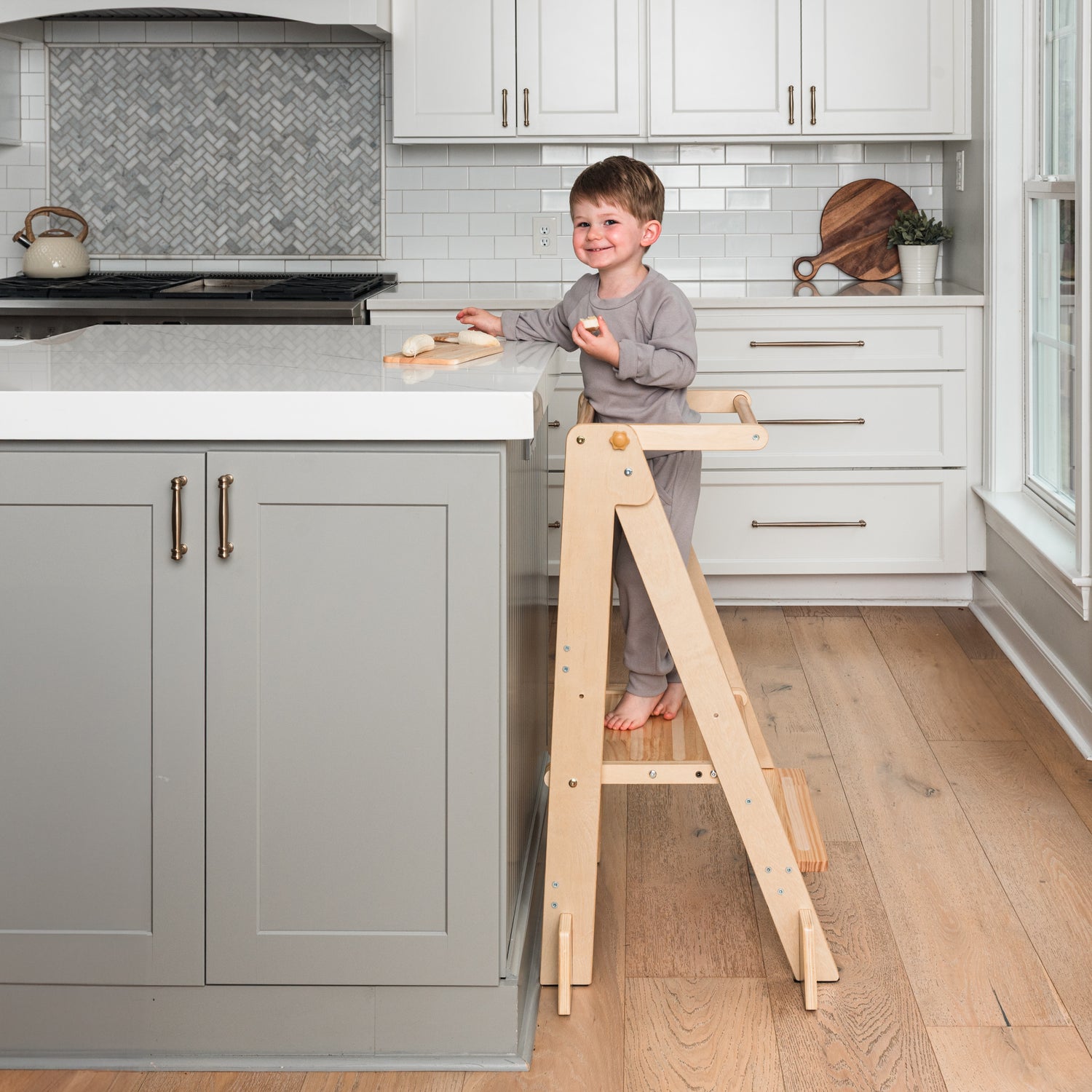 Child standing on a Ocodile toddler tower in a kitchen